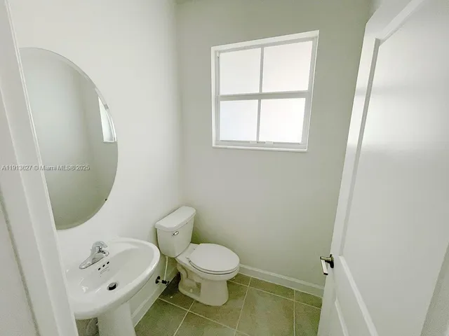 a white toilet sitting next to a bathroom sink and a mirror