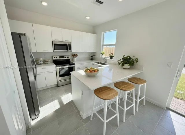 a white kitchen with a sink stainless steel appliances and cabinets