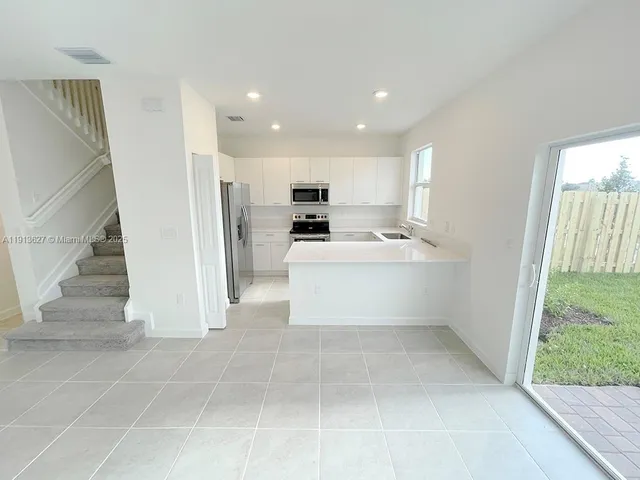 a kitchen with stainless steel appliances kitchen island granite countertop a refrigerator and a sink