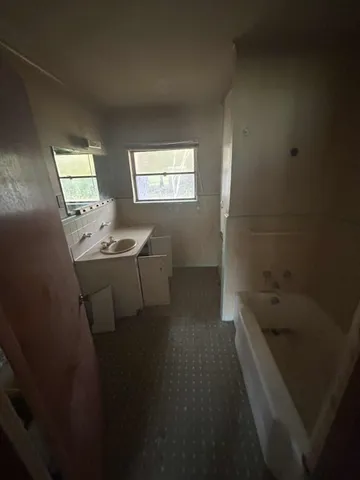 a bathroom with a sink a bathtub and a window