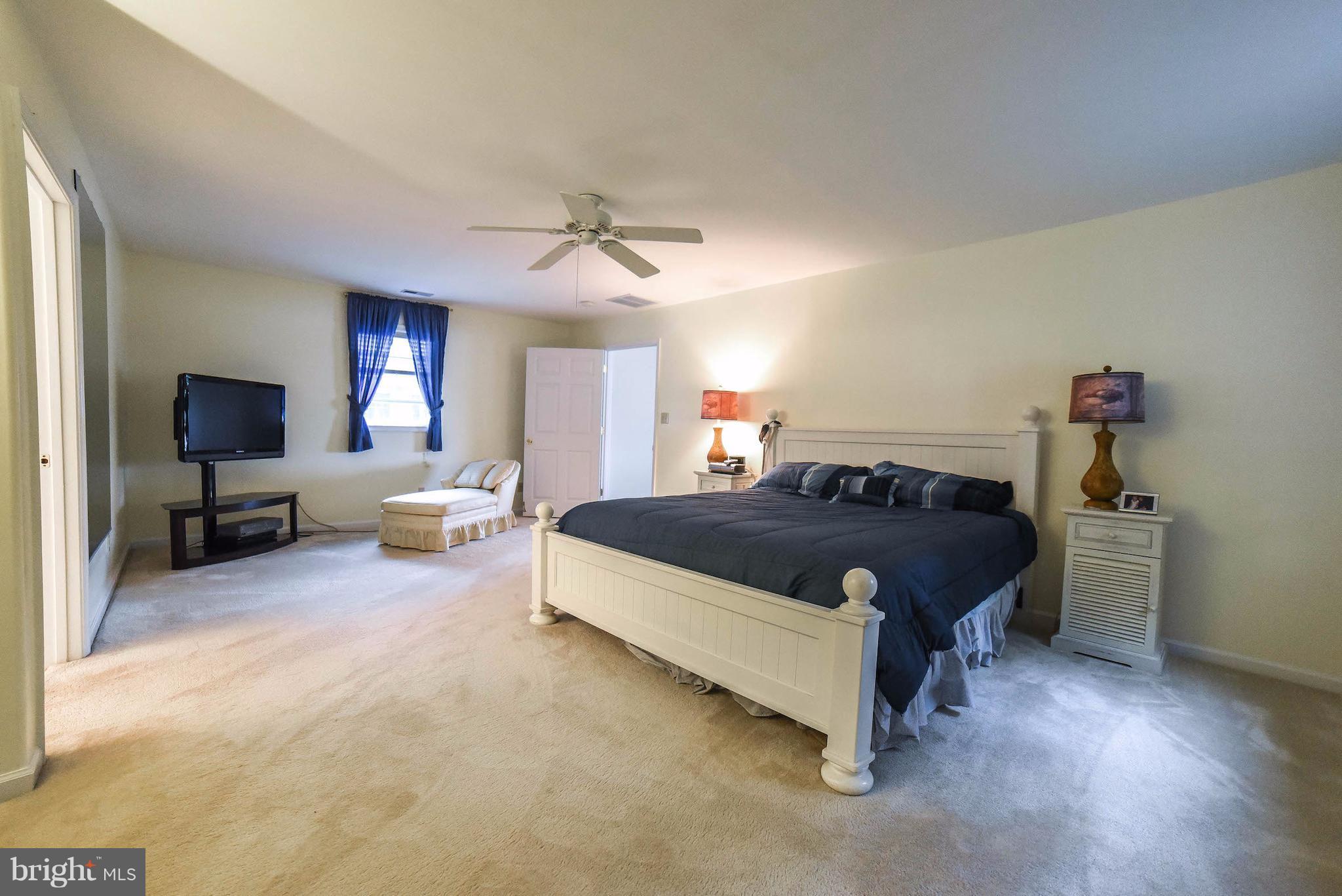16215 Osprey Cove Ln Ridge Ridge, MD 20680 - Photo 23 of 30 a spacious bedroom with a bed and a flat screen tv