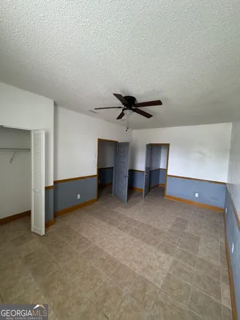 an empty room with a ceiling fan and window