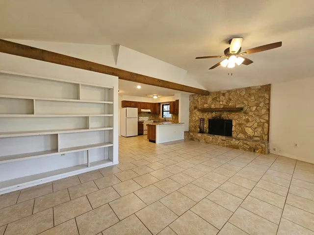 a view of a livingroom with a fireplace a chandelier fan and windows