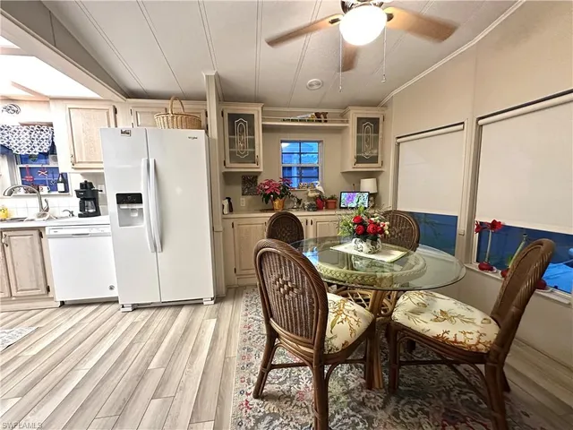 a dining room with furniture a kitchen a chandelier and wooden floor