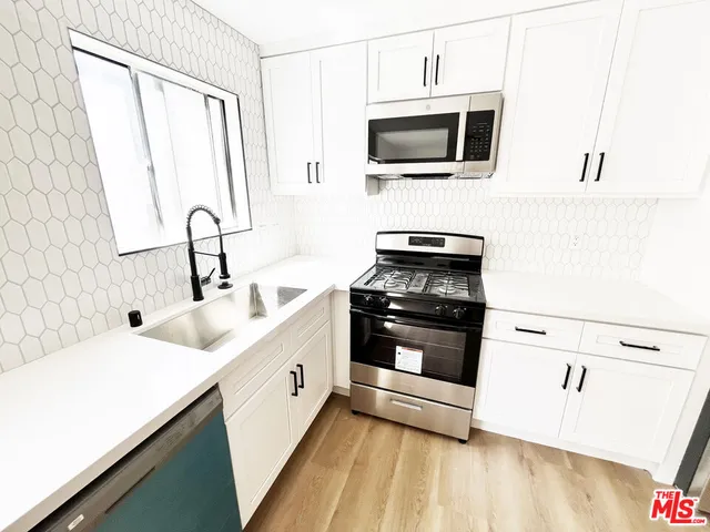 a kitchen with stainless steel appliances a stove microwave and sink