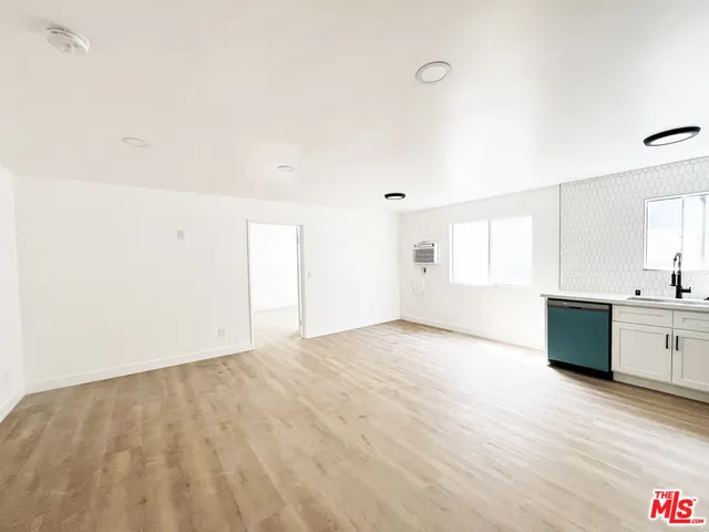 a view of an empty room with window and wooden floor