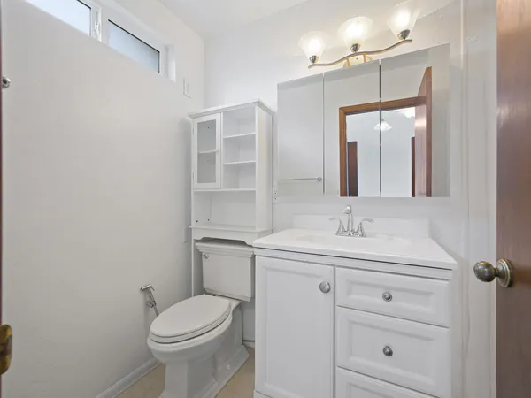 a bathroom with a toilet sink vanity and mirror