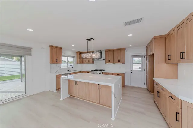 a large white kitchen with a stove top oven a sink a refrigerator and white cabinets