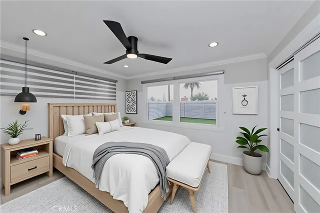 a large white bed sitting in a bedroom next to a window and a potted plant