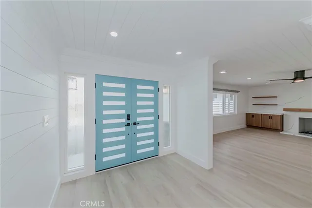 an empty room with wooden floor closet and windows