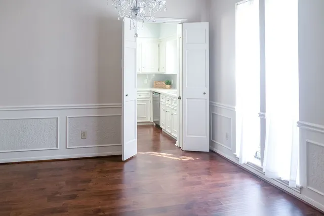 an empty room with wooden floor ceiling fan and windows
