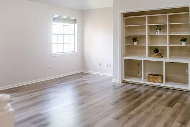 a view of a hallway with wooden floor and a window