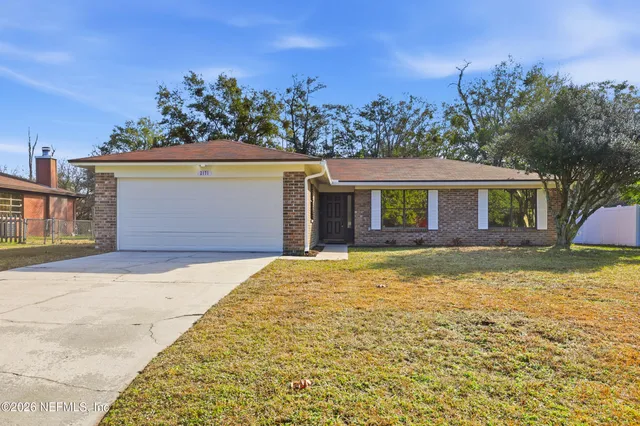 a front view of house with yard and trees in the background