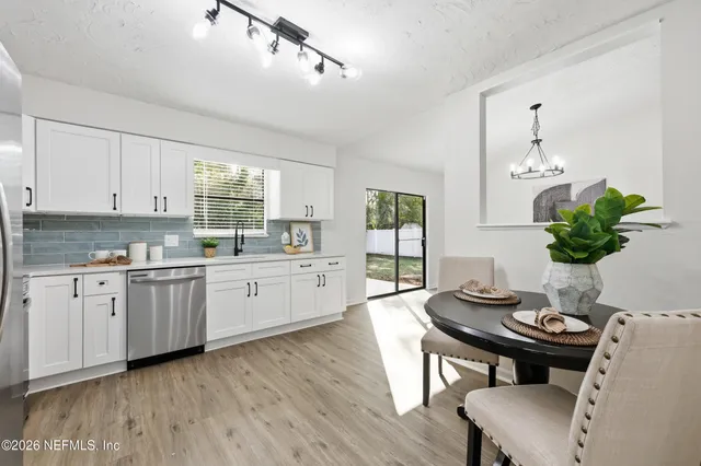 a kitchen with a dining table chairs and white cabinets