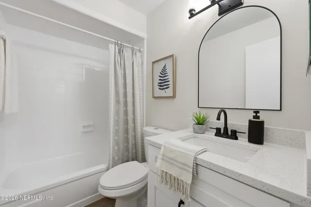 a bathroom with a granite countertop sink mirror vanity and toilet