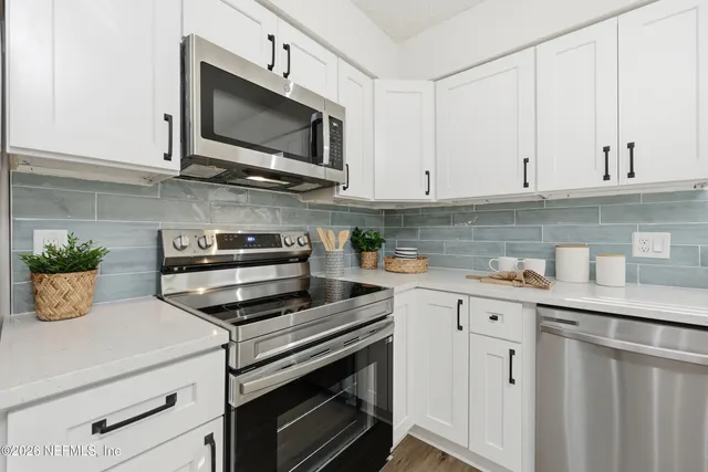 a kitchen with stainless steel appliances white cabinets and a stove top oven