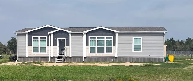 a front view of a house with a yard and trees