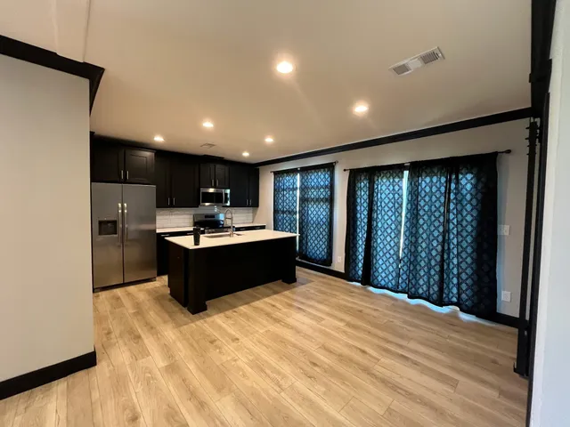 a large kitchen with kitchen island a sink dishwasher stove with wooden cabinets and floor