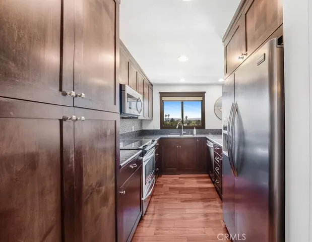 a kitchen with stainless steel appliances granite countertop a refrigerator a stove and a sink