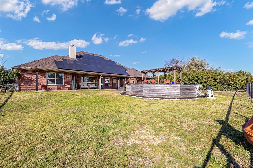 116 Miramar Circle Weatherford, TX 76085 - Photo 26 of 37 Rear view of house with 18.48KW Solar System featuring 42 Aptos solar panels and Enphase inverters. Roof replaced 2025 with Class 4 shingles. View of above-ground pool and cedar pergola.