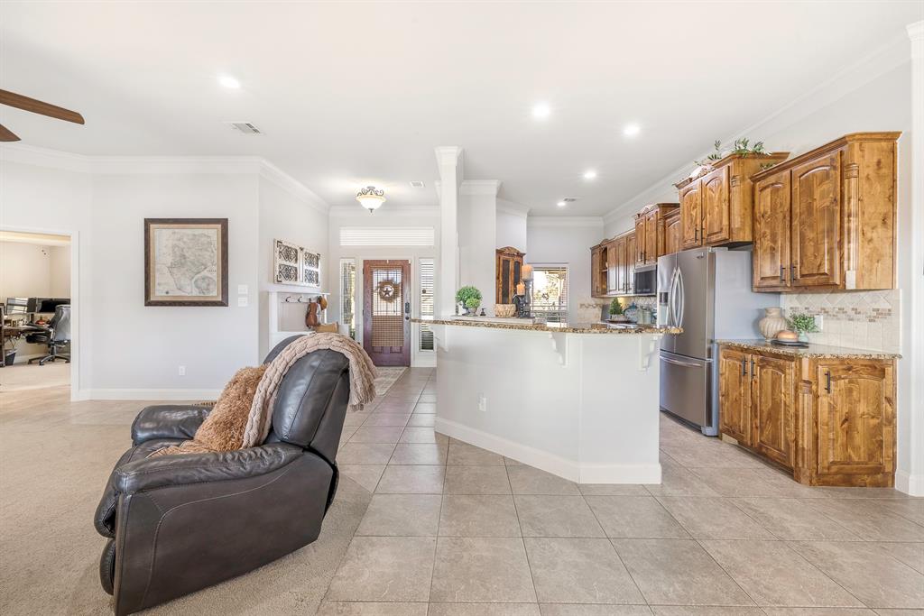 116 Miramar Circle Weatherford, TX 76085 - Photo 37 of 37 Open concept floorplan connects the entryway to the kitchen and living room. Kitchen features granite countertops, a desk space, crown molding, and a breakfast bar