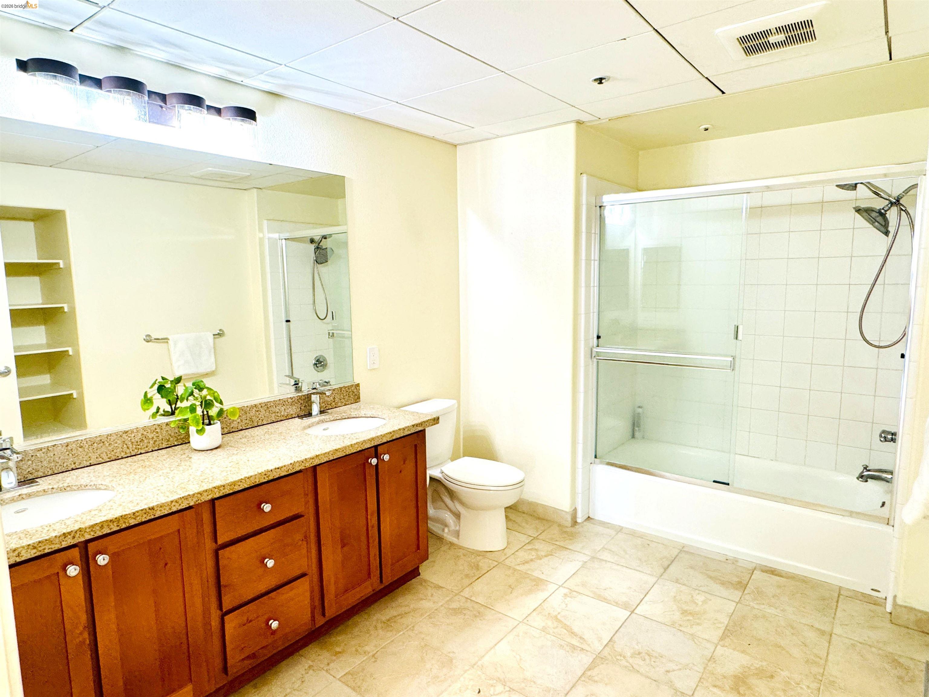 423 7th Street, Unit 303 Oakland, CA 94607 - Photo 14 of 19 a spacious bathroom with a granite countertop sink toilet mirror and shower