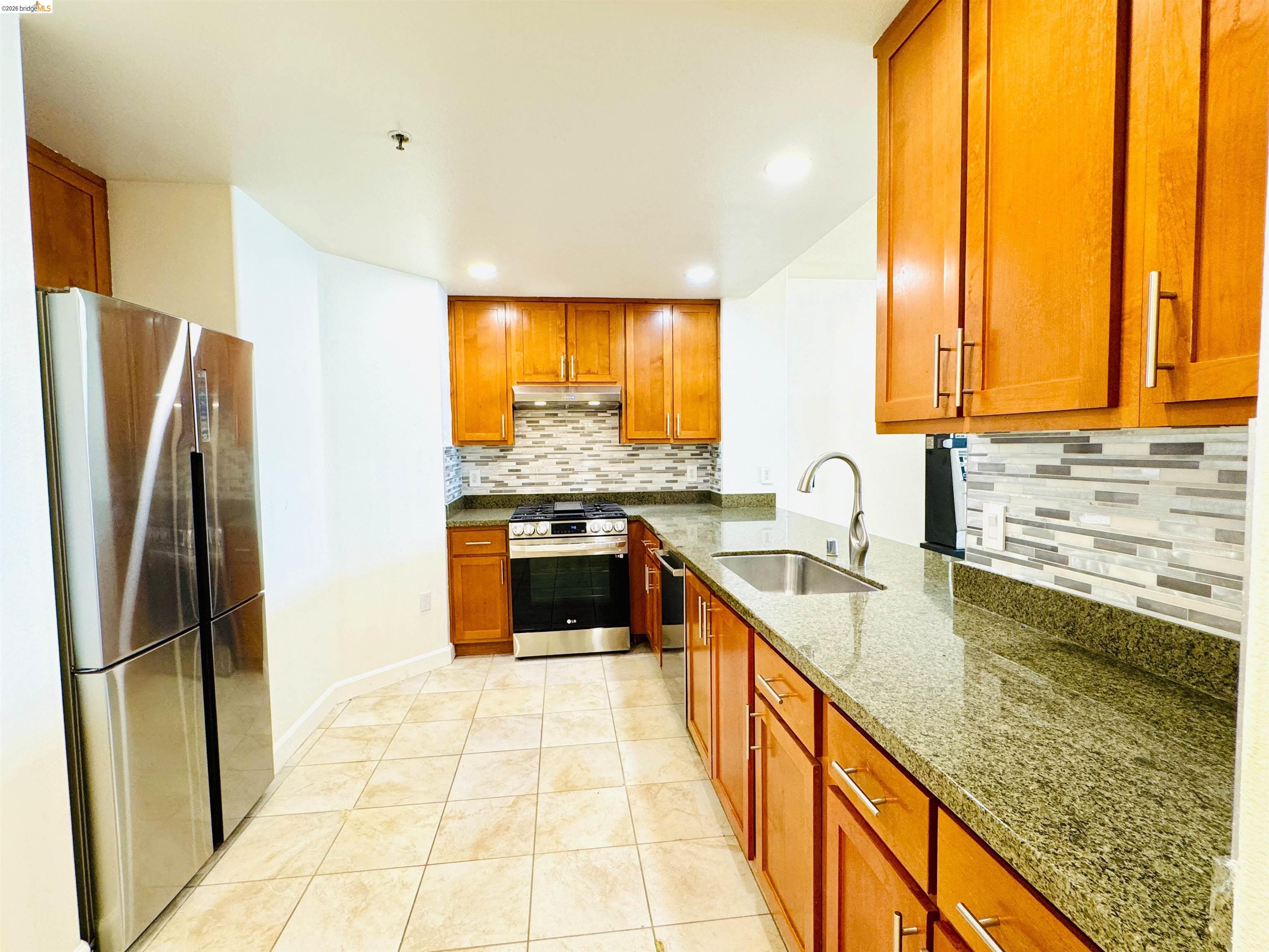 423 7th Street, Unit 303 Oakland, CA 94607 - Photo 10 of 19 a kitchen with stainless steel appliances granite countertop a stove a sink and a refrigerator