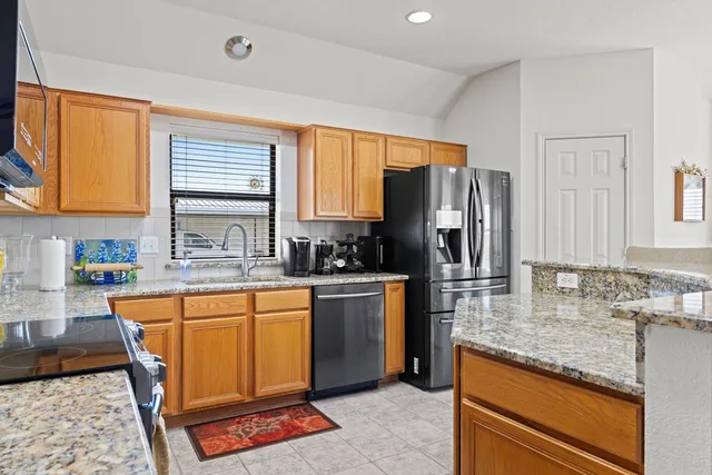 a kitchen with stainless steel appliances granite countertop a stove a sink dishwasher a refrigerator and cabinets with wooden floor