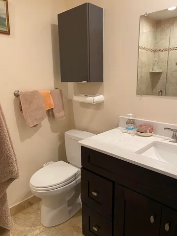 a bathroom with a granite countertop toilet sink and mirror