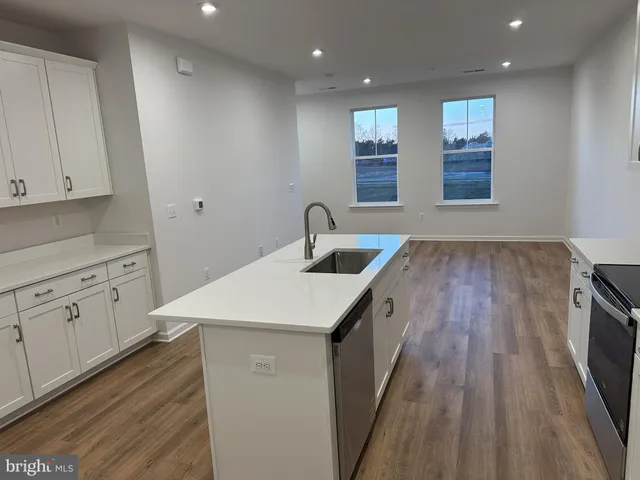 a kitchen with white cabinets a sink dishwasher and a stove with wooden floor