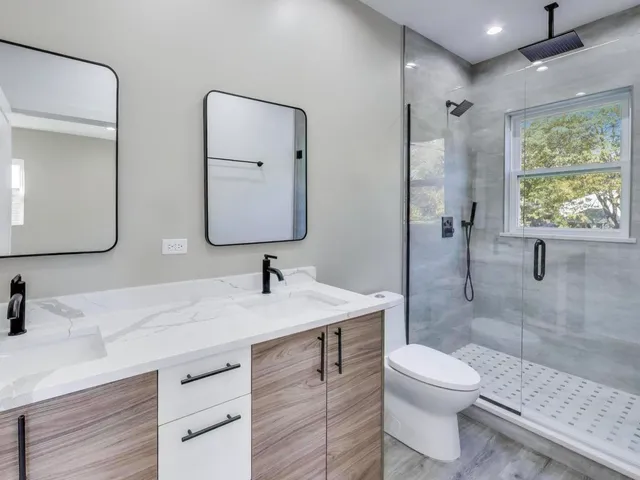 a bathroom with a toilet a sink a mirror and shower