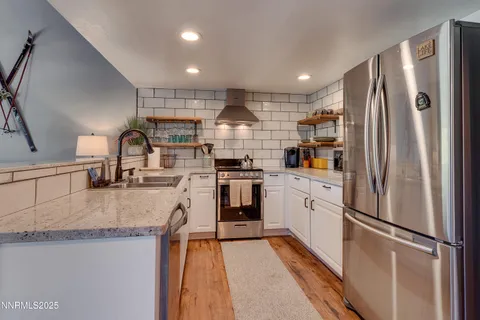 a kitchen with stainless steel appliances granite countertop a refrigerator a stove and a sink