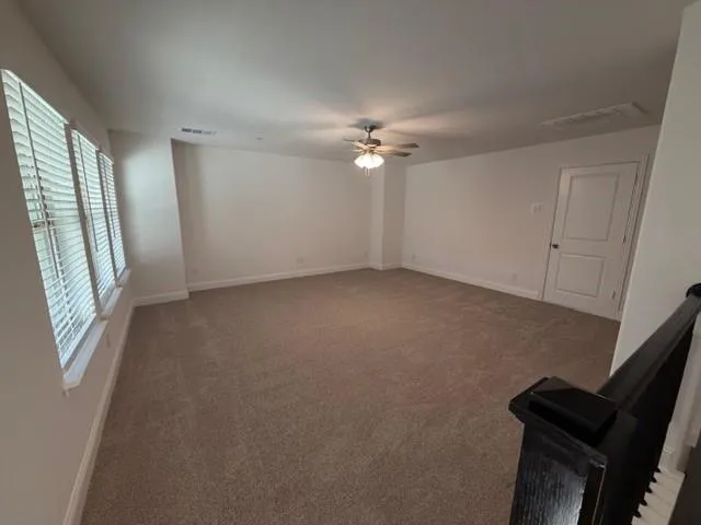 an empty room with windows and fan