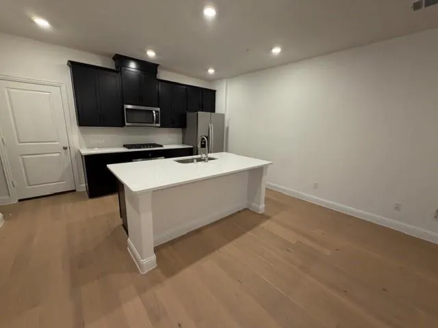 a large white kitchen with stainless steel appliances a large counter top
