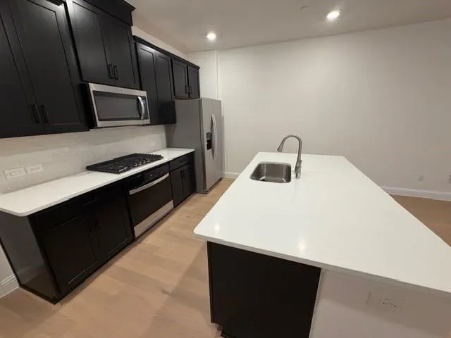 a kitchen with a sink and a stove top oven with wooden floor