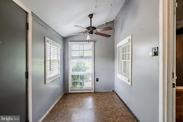 an empty room with windows and fan