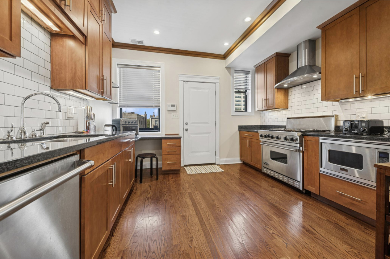 4834 North Kenmore Avenue, Unit 3N Chicago, IL 60640 - Photo 7 of 28 a kitchen with stainless steel appliances granite countertop wooden floors and white cabinets
