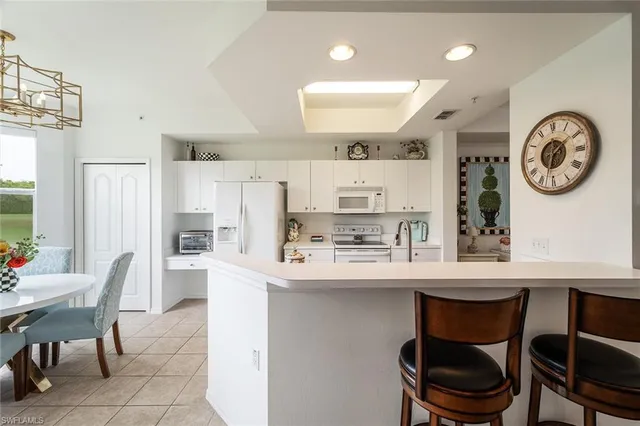 a white kitchen with a table chairs a stove a dining table and chairs