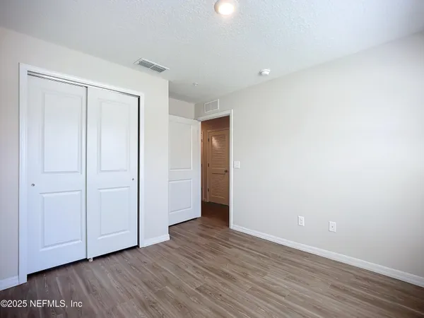 a view of an empty room with wooden floor and closet