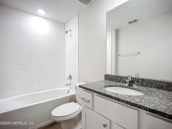 a bathroom with a granite countertop sink a toilet and shower