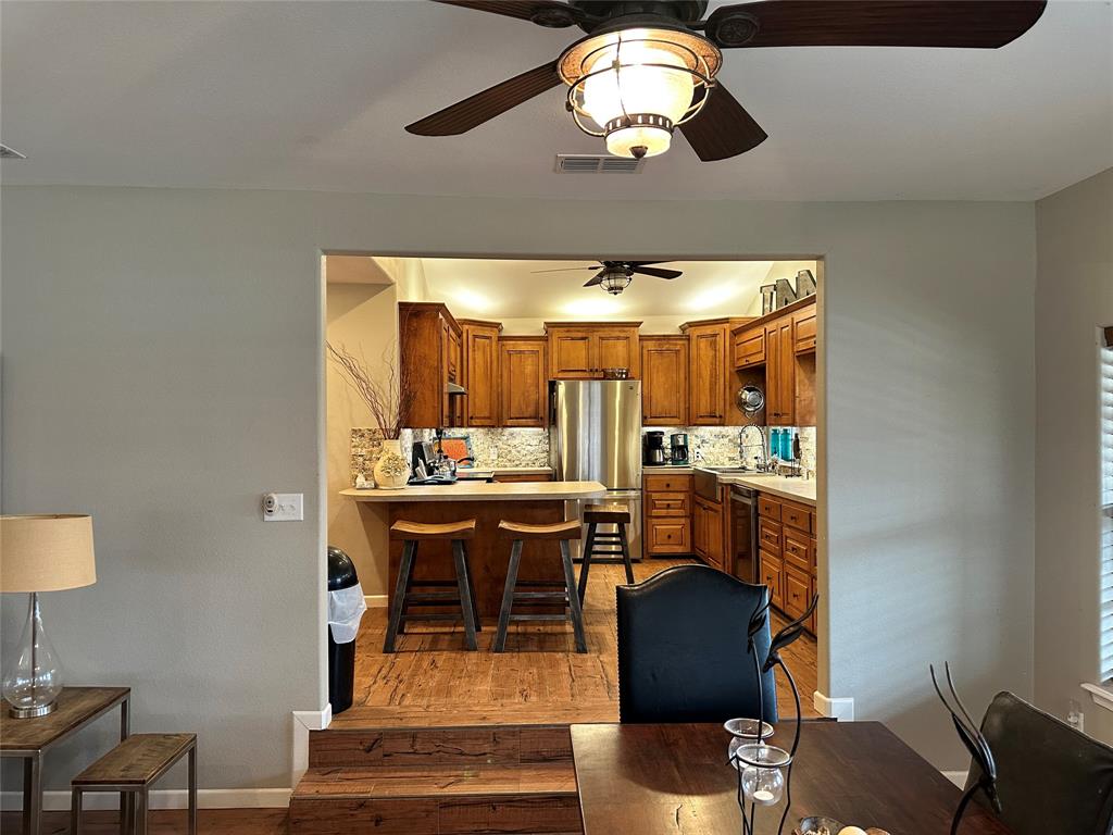 11001 West Lake Road Abilene, TX 79601 - Photo 21 of 40 Kitchen featuring freestanding refrigerator, ceiling fan, brown cabinetry, visible vents, and decorative backsplash