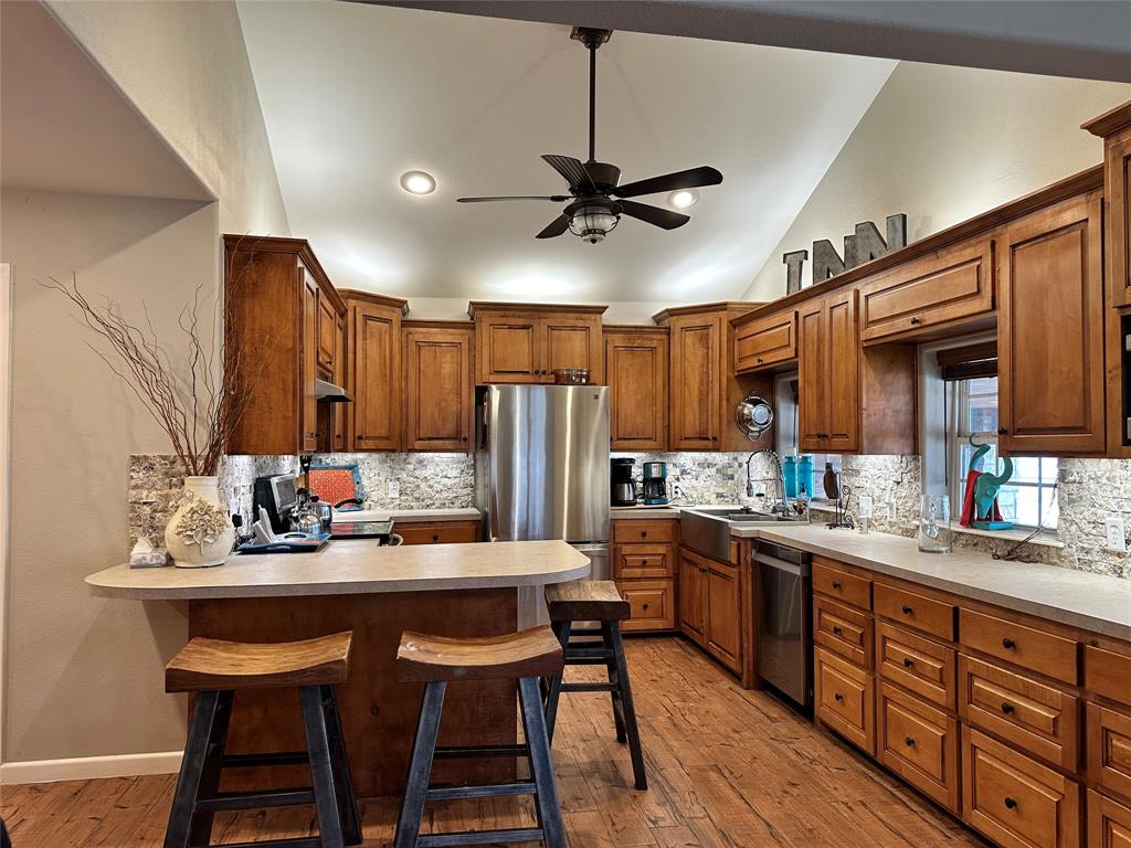 11001 West Lake Road Abilene, TX 79601 - Photo 22 of 40 Kitchen with stainless steel appliances, a ceiling fan, a sink, light wood-type flooring, and vaulted ceiling