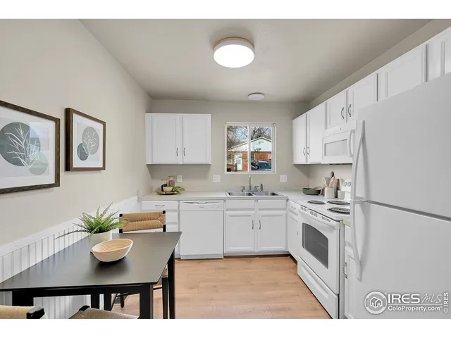 a kitchen with stainless steel appliances granite countertop a stove a sink dishwasher and white cabinets with wooden floor