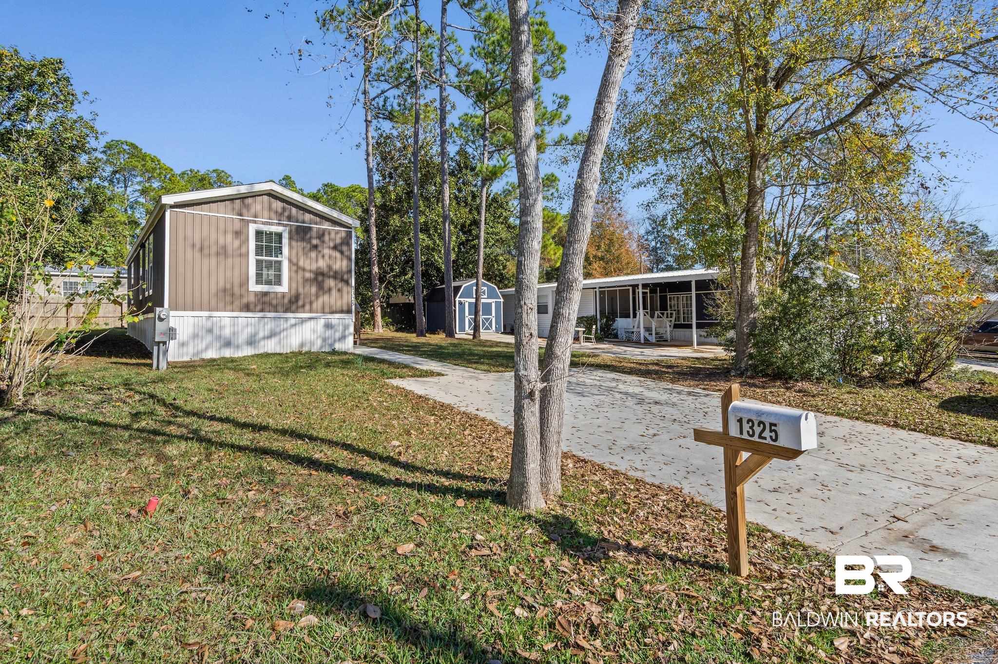 1325 Ridgewood Drive Lillian, AL 36549 - Photo 16 of 32 View of green lawn featuring a storage unit, a patio area, and a sunroom