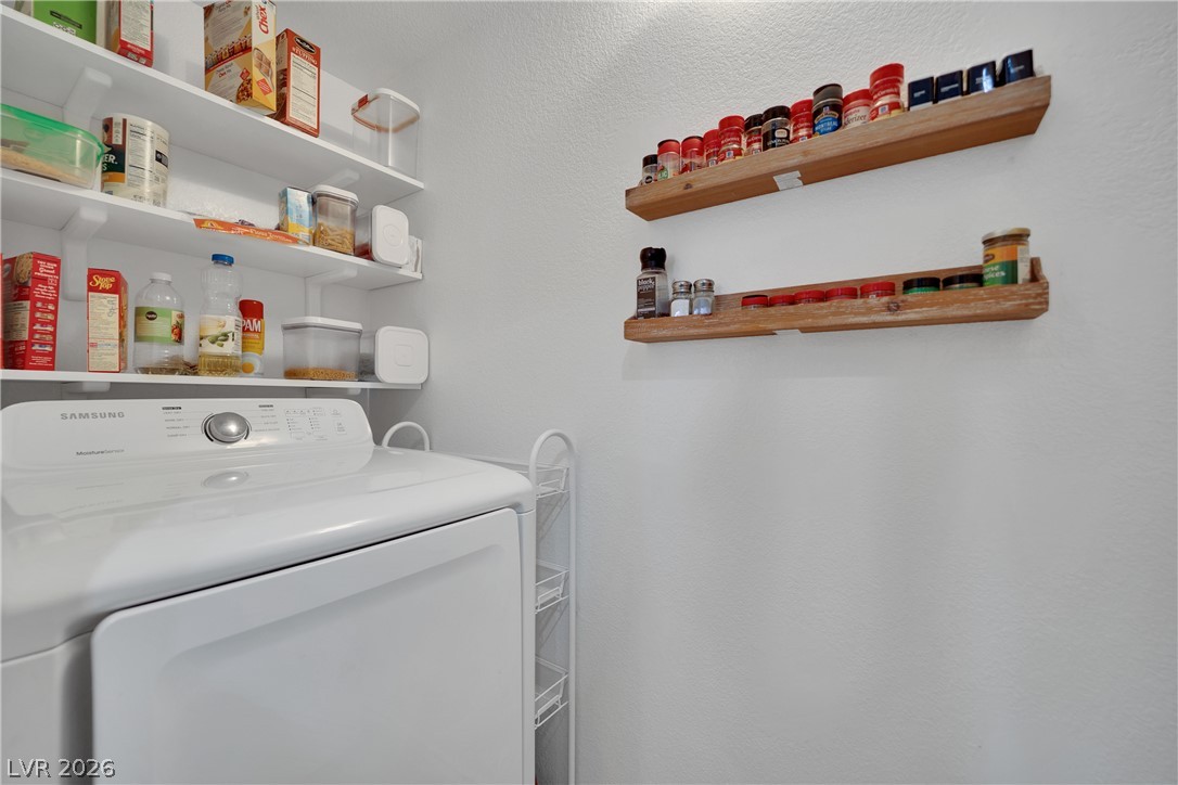 7570 West Flamingo Road, Unit 115 Las Vegas, NV 89147 - Photo 14 of 34 Functional laundry area featuring white shelving and a modern washer with convenient storage.