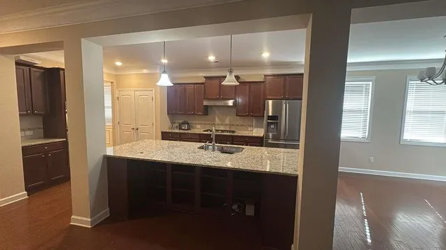 a kitchen with kitchen island granite countertop a sink appliances and cabinets