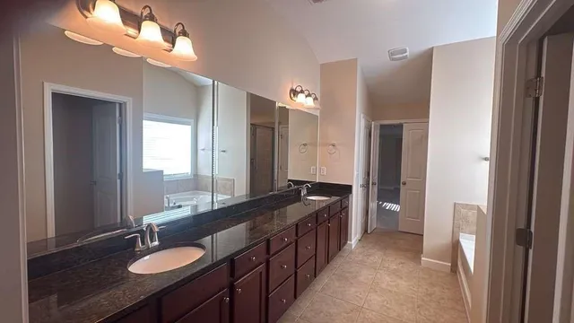 a spacious bathroom with a double vanity sink a mirror and a shower
