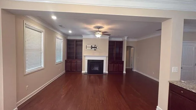 a view of a livingroom with a fireplace a ceiling fan and wooden floor