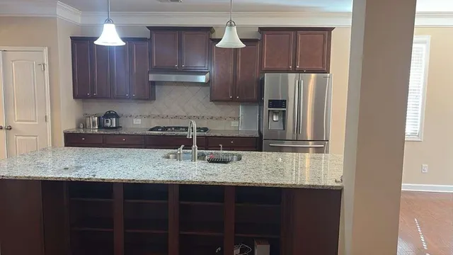 a kitchen with stainless steel appliances granite countertop a sink refrigerator and cabinets