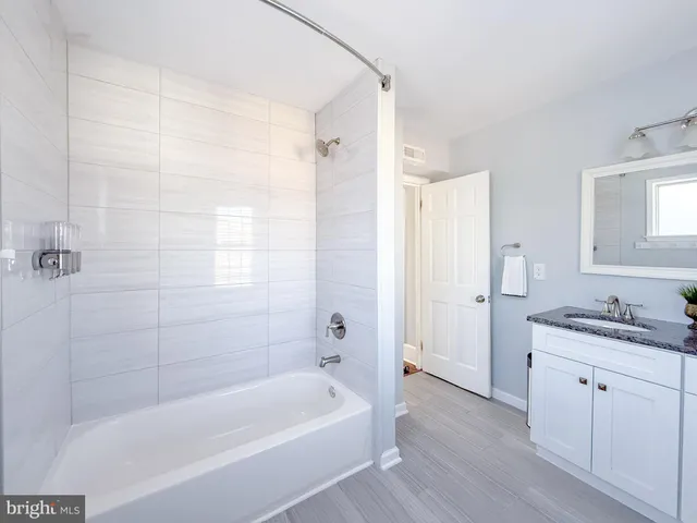a bathroom with a granite countertop bathtub shower sink and mirror